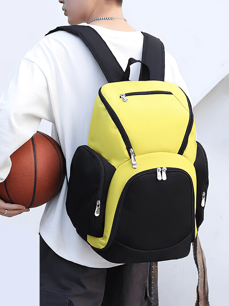 Person carrying Waterproof Lightweight Large Capacity Football Backpack SF0870 in black and yellow, holding a basketball.